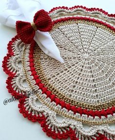 a crocheted doily with a red bow on the top and white napkin