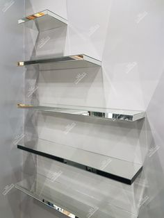 three glass shelves are stacked on each other in front of a white wall with gold trim