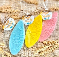 four different colored soaps sitting on top of a table next to some ears of wheat