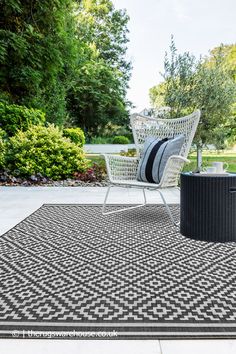 a black and white area rug with two chairs on the ground in front of trees