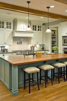 A large open cream colored kitchen with a sage green kitchen island. Kitchen Semi Island, Thick Kitchen Island Countertop, Island With Seating On 3 Sides, Kitchen Island Seating For 6, Unique Islands For Kitchen, Island Seating Kitchen, Square Island Kitchen, Kitchen Island With Seating For 6