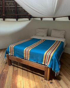 a bed with a blue blanket on top of it in a room that has wooden floors