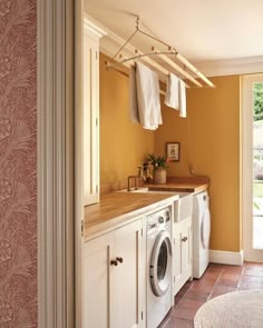 a washer and dryer in a small room with yellow wall paper on the walls