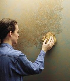 a woman is cleaning the wall with a sponge