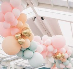 some balloons are hanging from the ceiling in a room with white and pink walls, along with gold accents