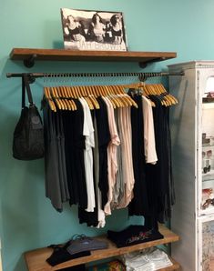 a closet with clothes hanging on the rail and other items sitting on shelves in front of it