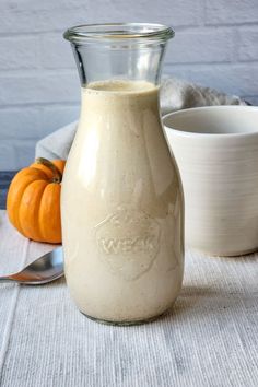 a glass bottle filled with liquid sitting on top of a table next to a bowl and spoon