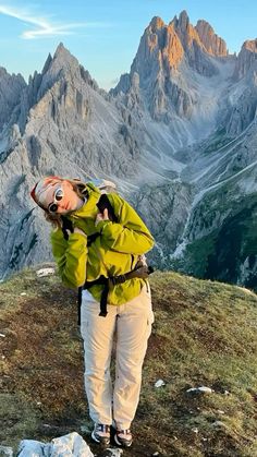 a woman standing on top of a grass covered hillside