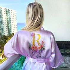 Experience the luxury of our kimono floral robe with a unique monogram design. This silk robe for women is not just a custom bathrobe, it's a statement of elegance and sophistication. Perfect as a bridal robe for the bride, it adds a touch of glamour to your special day. Our women's bathrobe is made from the finest satin, ensuring a comfortable fit and a luxurious feel. The bride robe is adorned with a beautiful floral pattern, making it a stunning floral robe. Personalize your robe with our per Wedding Robe With Kimono Sleeves For Spring, Spring Wedding Robe With Kimono Sleeves, Pink Robe With Kimono Sleeves For Wedding, Spring Wedding Sleepwear With Kimono Sleeves, Summer Wedding Satin Robe, Spring Wedding Satin Robe, Feminine Satin Robe For Summer, Feminine Satin Summer Robe, Spring Wedding Satin Kimono