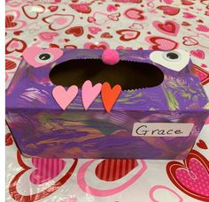 a purple box with hearts and eyes on it sitting on a table covered in paper