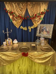 a table set up for a party with plates and desserts on it, in front of a backdrop that says our guest