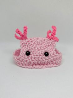 a pink knitted object with black eyes and antlers