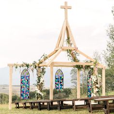 a wooden structure with stained glass windows and greenery on the top is set up for an outdoor ceremony