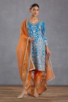 Persian blue straight kurta with all-over gota patti embroidery. Comes with orange pant and sheer dupatta.
Components: 3
Pattern: Embroidery and Print
Type Of Work: Hand Adda Work, Gota and Digital Bhagalpuri Print
Neckline: V neck
Sleeve Type: Full
Fabric: Kurta and Pant: Slub Silk and Dupatta: Silk Organza
Color: Blue,Orange
Other Details: 
Dupatta with scallop lace border
Kurta with side slits
Pant with scallop hem
Occasion: Wedding - Aza Fashions Embroidery Samples, Sheer Dupatta, Traditional Suit, Persian Blue, Scallop Hem, Embroidery Suits Design, Boutique Dress Designs, Straight Kurta, Embroidery Designs Fashion