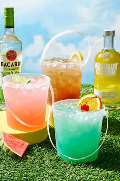 three different types of drinks sitting on top of a grass covered field next to each other