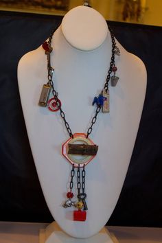 a white mannequin holding a necklace with various items on it's neck