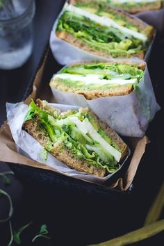 two sandwiches with lettuce and cheese in wrappers