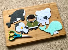 some felt animals are sitting on a cutting board