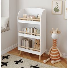 a stuffed giraffe sitting next to a white book shelf with books on it