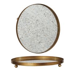 a round mirror sitting on top of a wooden tray next to a gold rimmed table