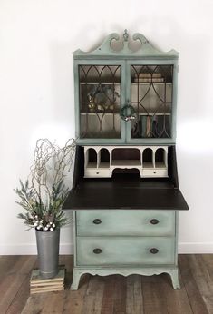 an old china cabinet with glass doors on the top and bottom, next to a potted plant