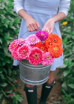 a woman holding a bucket full of flowers