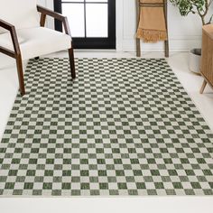 a checkered area rug in a living room next to a chair and table with a potted plant on it