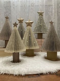 small christmas trees made out of folded book pages on a white rug in front of a window