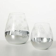 two glass vases with snowflakes on them sitting next to each other in front of a white wall