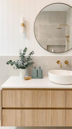 a bathroom with a round mirror above the sink and wooden cabinetry on the side