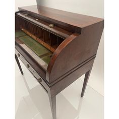 an old wooden desk with glass top and drawers on it's sides, in a white room