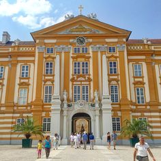 people are walking around in front of an old building with yellow and white stripes on it