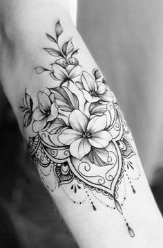 a black and white photo of a flower tattoo on the arm with an intricate design