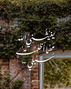 an arabic calligraphy on a brick wall with ivy growing up it's side