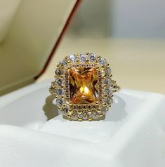 a fancy ring with an orange diamond surrounded by white and yellow cubics on top