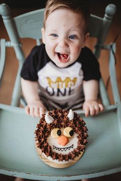 a baby sitting in a blue chair with a cake