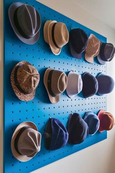 several hats are hanging on a blue peg board