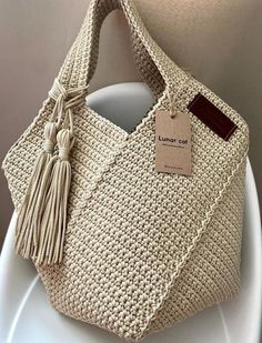 a crocheted bag with a tag hanging from it's side on a white plate