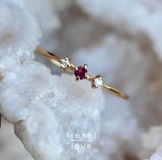 a gold ring with three stones on it sitting on top of some white rock next to a piece of crystal