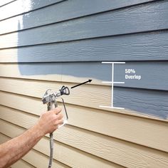 a man spray painting the side of a house with blue siding and white paint on it