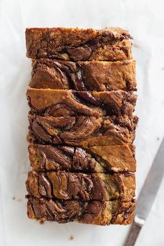 slices of chocolate swirled banana bread stacked on top of each other with a knife next to it