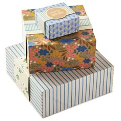 three boxes stacked on top of each other with different designs and colors, one has a flower pattern