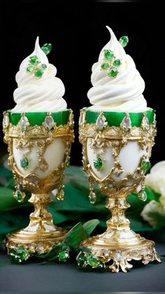 two green and white cupcakes sitting on top of gold pedestals next to each other