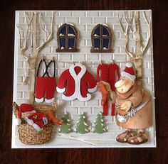 a christmas scene made out of paper with santa hats and clothes hanging on the wall