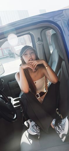 a woman sitting in the back seat of a blue truck with her hand on her chin