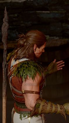 an image of a woman in costume holding a spear and wearing leaves on her back