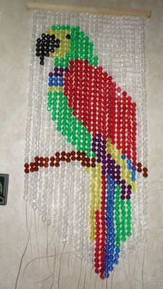 a beaded wall hanging with a colorful parrot on it's side and beads attached to the back