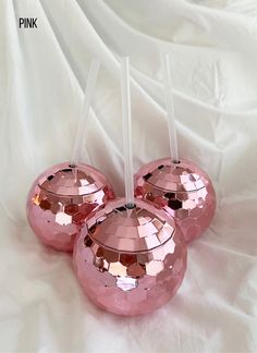 three shiny pink candlesticks sitting on top of a white cloth covered tablecloth