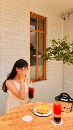 a woman sitting at a table with food and drink