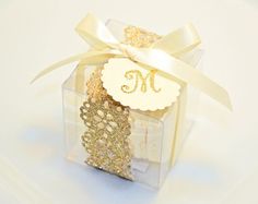 a clear box with gold sequins and a white ribbon tied around the top